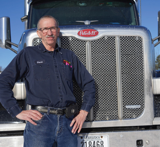 Employee standing in front of semi-truck front.